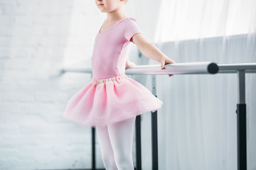 cropped shot of kid in pink tutu practicing ballet in studio