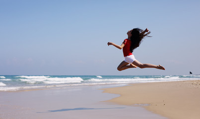 Portrait of aborable 12 years old girl jumping on the beach in summer day
