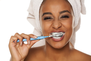 portrait of a happy young dark-skinned woman brushing her teeth on a white background