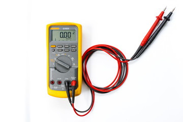 Yellow Digital multimeter with probes on white background , A multimeter  is an electronic...