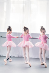 Naklejka premium back view of graceful little ballerinas practicing ballet in studio