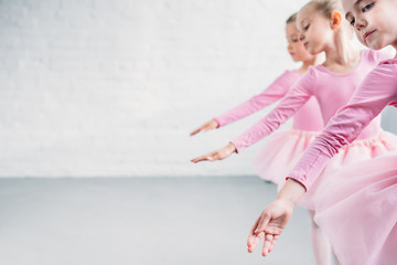 side view of graceful little ballerinas dancing together in ballet school - Powered by Adobe
