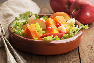 Fall salad with apple ,pumpkin and melogran on rustik background.