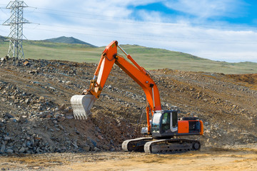 The excavator is building a new road near the power transmission line.