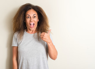 Curled hair brazilian woman pointing with hand and finger up with happy face smiling