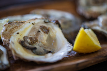 Oysters with lemon on wooden plate.