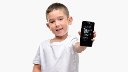 Dark haired little child holding broken smartphone with a happy face standing and smiling with a confident smile showing teeth