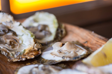 Oysters with lemon on wooden plate.