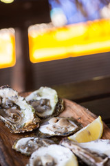 Oysters with lemon on wooden plate.
