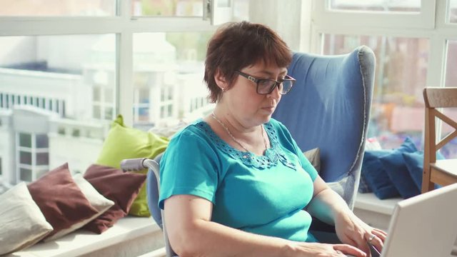 Businesswoman in wheelchair working on laptop at home