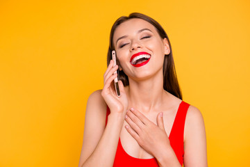 Close up portrait of trendy young woman laughing while talking on the cellular  isolated on yellow background