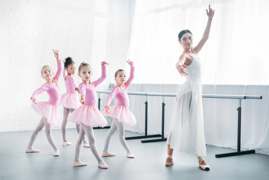 young teacher practicing ballet with adorable kids in pink tutu skirts