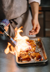 Chef cooking preparing food with fire torch.