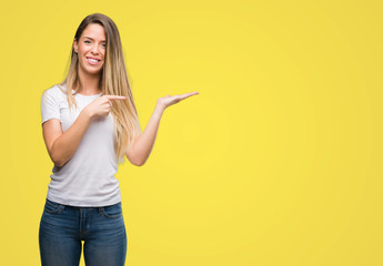 Beautiful young woman wearing t-shirt and jeans very happy pointing with hand and finger