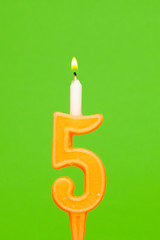 Colorful wax birthday candle  on green background