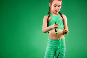 Sport concept. Kid girl doing fitness exercises on green background.