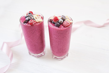 Two glasses of pink fruit smoothies milkshake or smoothie or cocktail on a white wooden background. Healthy juicy vitamin drink diet or vegan raw food concept