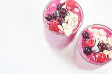 Two glasses of pink fruit smoothies milkshake or smoothie or cocktail on a white wooden background. Healthy juicy vitamin drink diet or vegan raw food concept