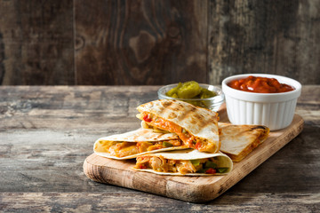 Mexican quesadilla with chicken, cheese and peppers on wooden table. Copyspace