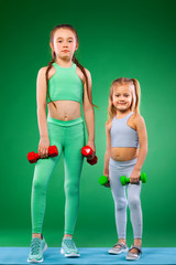 Children girls doing fitness exercises on green background together