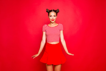 Adorable fancy young girl wear in red skirt and striped tshirt stand upright look at the camera isolated on red backgroung