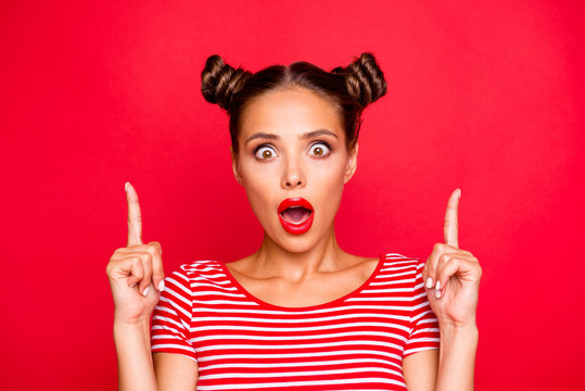 Close up portrait of astonished girl with wide open mouth gesturing index fingers up isolated on red background. Advertisement concept