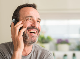 Middle age man using smartphone with a happy face standing and smiling with a confident smile...