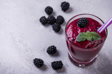 Blackberry natural  smoothie with mint and fresh berries in glasses on grey background