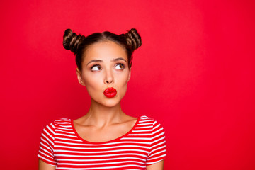 Attractive young girl with nice make up wearing striped tshirt puffed up her lips and looked up isolated on bright red background with copy space