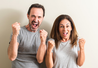 Middle age couple, woman and man screaming proud and celebrating victory and success very excited, cheering emotion