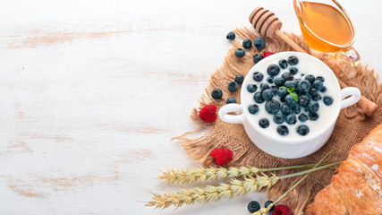 Fototapeta na wymiar Yogurt with Blueberry. Breakfast. On a wooden background. Top view. Free space for text.