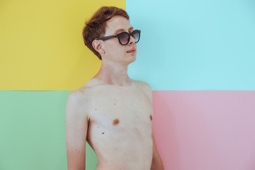 Man model with sunglasses on solid colored background with naked body. Pastel palette. Fashion...
