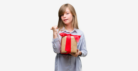 Young blonde toddler holding a present pointing with hand and finger up with happy face smiling