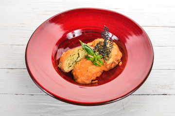 Cabbage rolls with tomato sauce in a red plate. On a wooden table. Top view. Copy space.