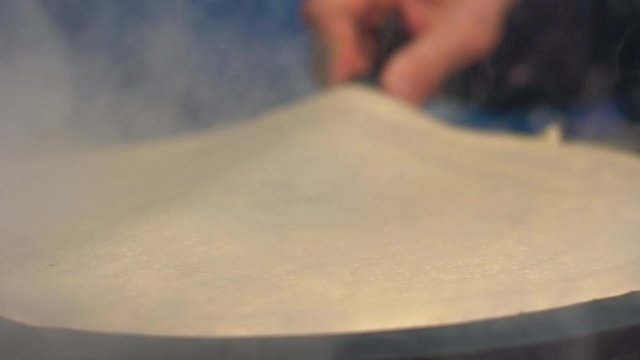 Slow motion of vendor man cooking crepes pancakes in Paris street. Close-up of tasty crepe dessert. Cheff is cooking a pancake made on a metal griddle. The concept of delicious fast food-Dan