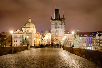 Fototapeta na wymiar Charles Bridge, The Old Town Bridge Tower, and the St. Francis of Assisi Church lit up at night