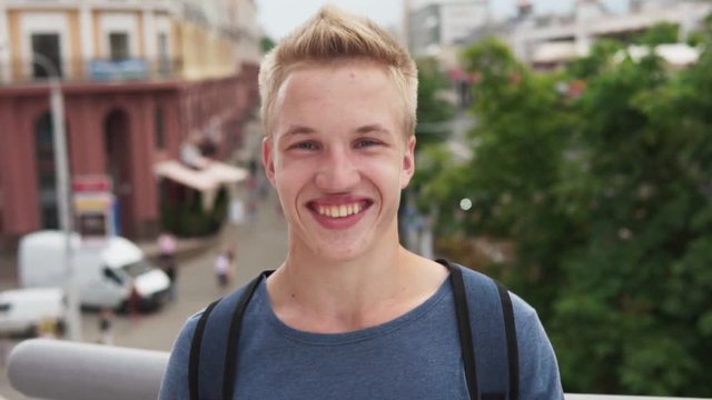 Young handsome blond man smiling at urban street