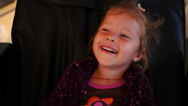Little kid girl have fun laughing enjoy to derive pleasure sitting in the massage chair