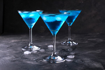 Blue cold cocktails  drink with ice cubes  on a dark background