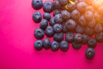 Berries in summer, a source of vitamins. Close - up of ripe blueberries on pink background
