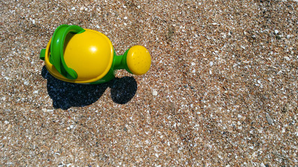 Toy shovel, bucket and watering can on the sea coast