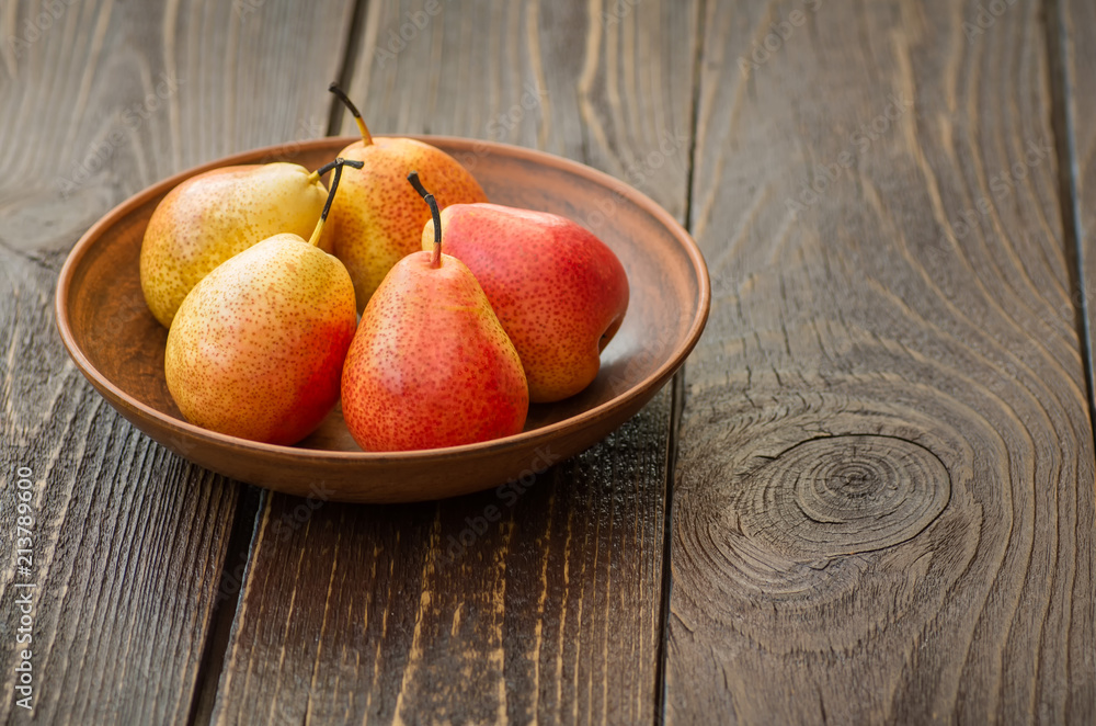 Wall mural fresh ripe pears in a clay plate on a wooden table.