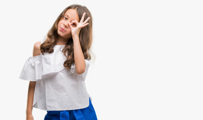Brunette hispanic girl doing ok gesture with hand smiling, eye looking through fingers with happy face.