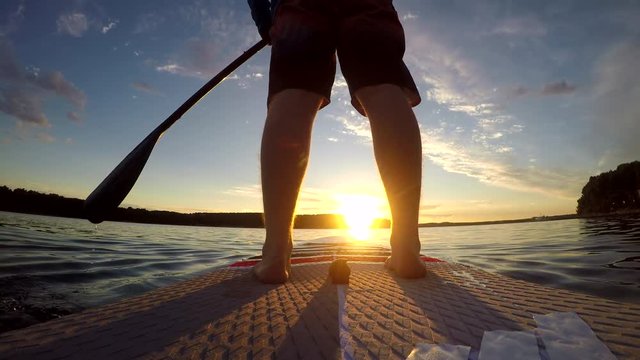 4K. Man paddling SUP at ocean sunset