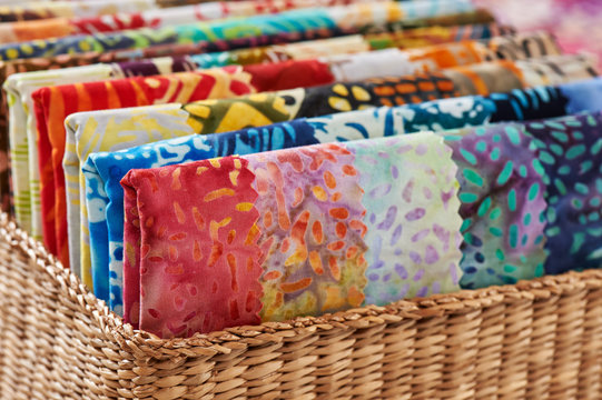 Folded bright pieces of quilting batik fabrics in a basket, macro