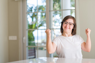 Down syndrome woman at home screaming proud and celebrating victory and success very excited,...