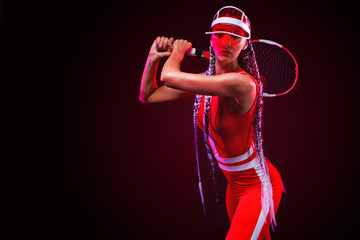 Tennis player. Beautiful woman athlete with racket in red costume and hat isolated on black background. Fashion and sport concept.