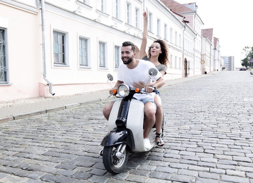 Full length side view of happy couple riding on retro motorbike