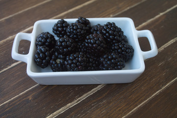 blackberries on white tray on a wooden table seen close up