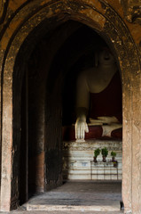 Fototapeta premium A larger than life statue of a sitting Buddha displays the touching Earth hand gesture, enclosed in a shrine in Bagan Temple Valley, Myanmar.